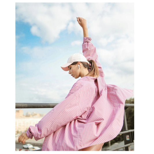 Woman in pale pink cap and pink shirt outdoors 